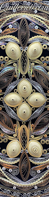 Circular quilled design in muted metallic color tones close-up detail view.