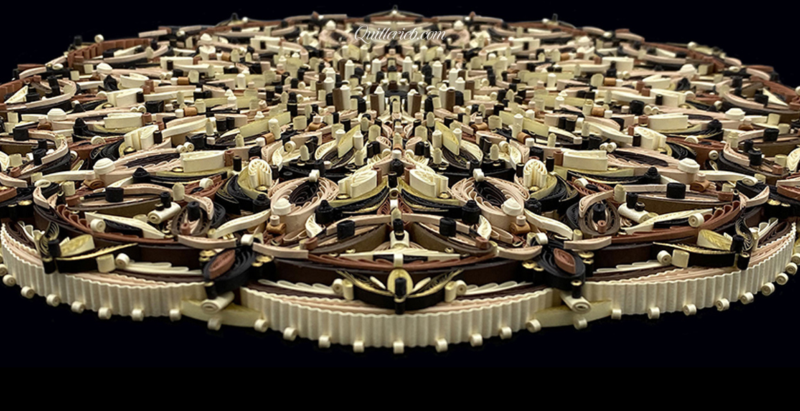 Circular quilled design in brown tones perspective close-up slanted backwards view.