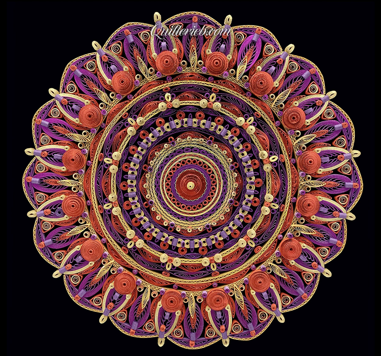 Circular quilled design in red, purple and yellow tones full view.