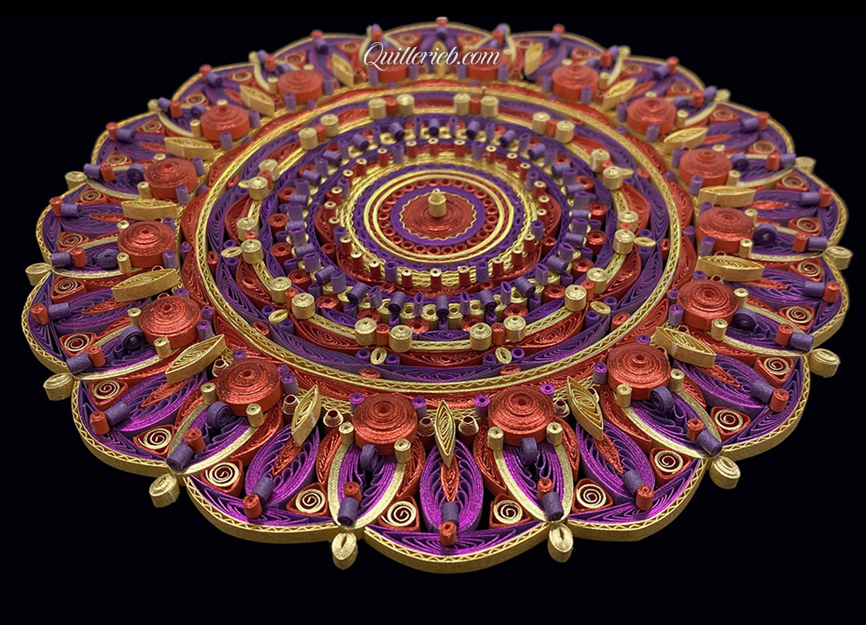 Circular quilled design in red, purple and yellow tones full slanted backwards view.