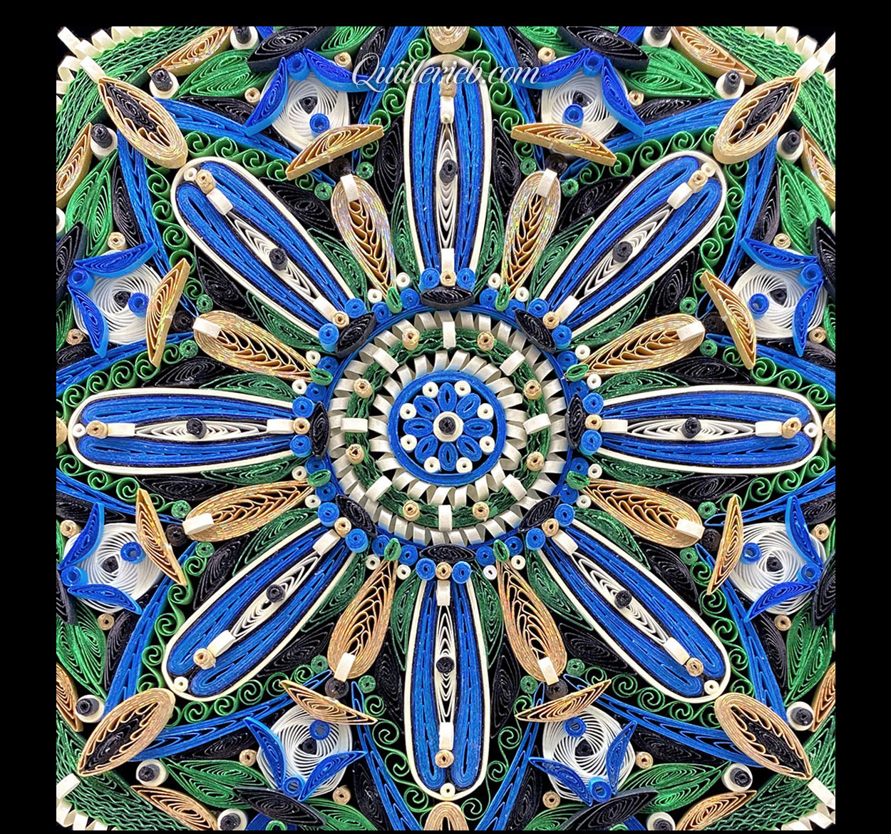 Circular quilled design in green, blue and white tones close-up view.