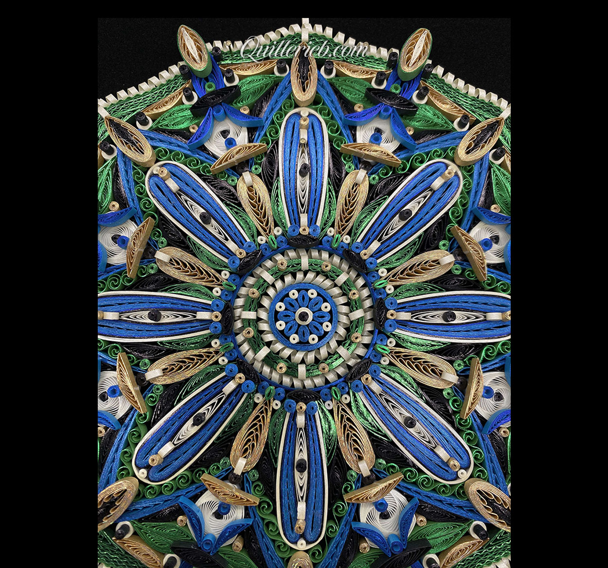 Circular quilled design in green, blue and white tones close-up top view.