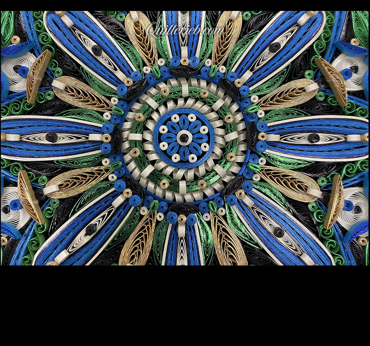 Circular quilled design in green, blue and white tones center close-up view.
