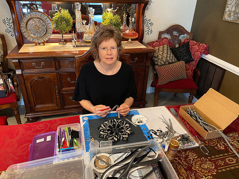 Bio photo of Quillerie.b owner Beth Reece sitting at the table with her quilling project and equipment.