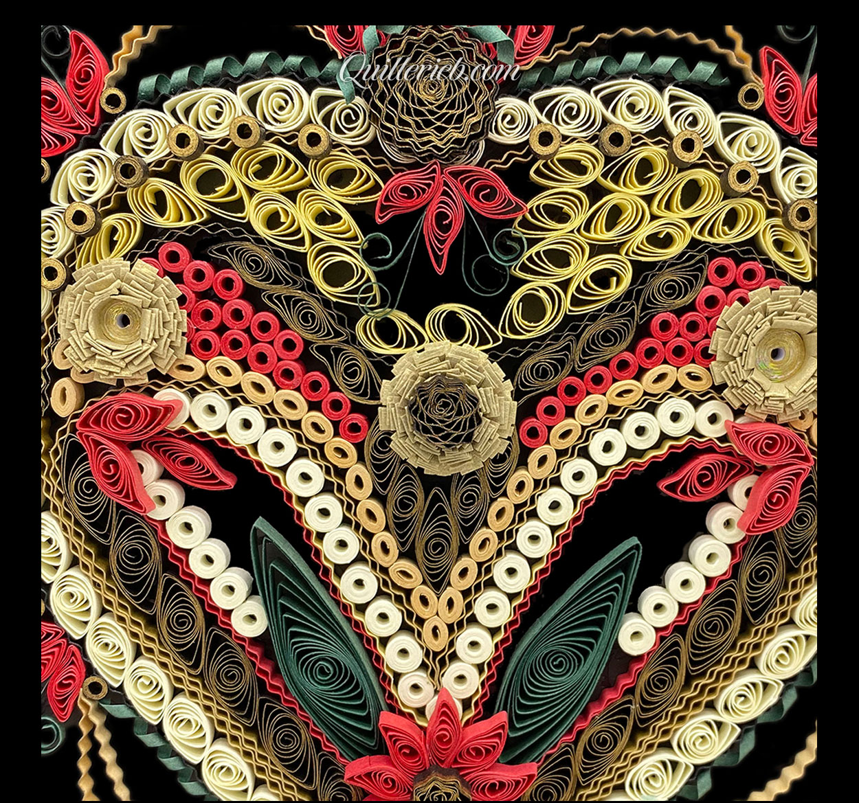 Heart-shaped quilling design in reds, creams, greens and browns close-up view.