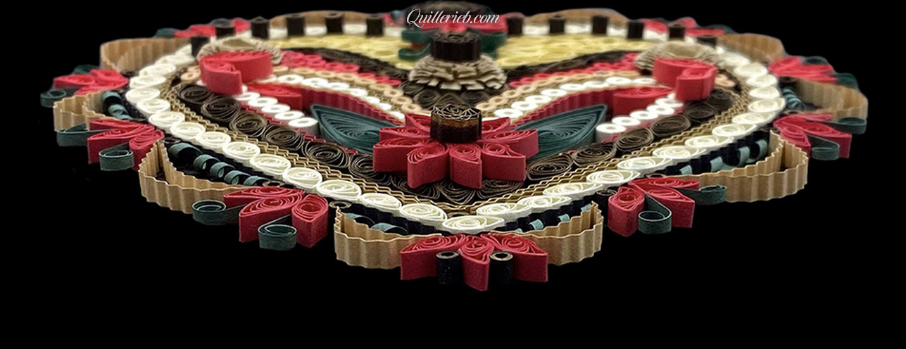 Heart-shaped quilling design in reds, creams, greens and browns perspective view slanted backwards view.
