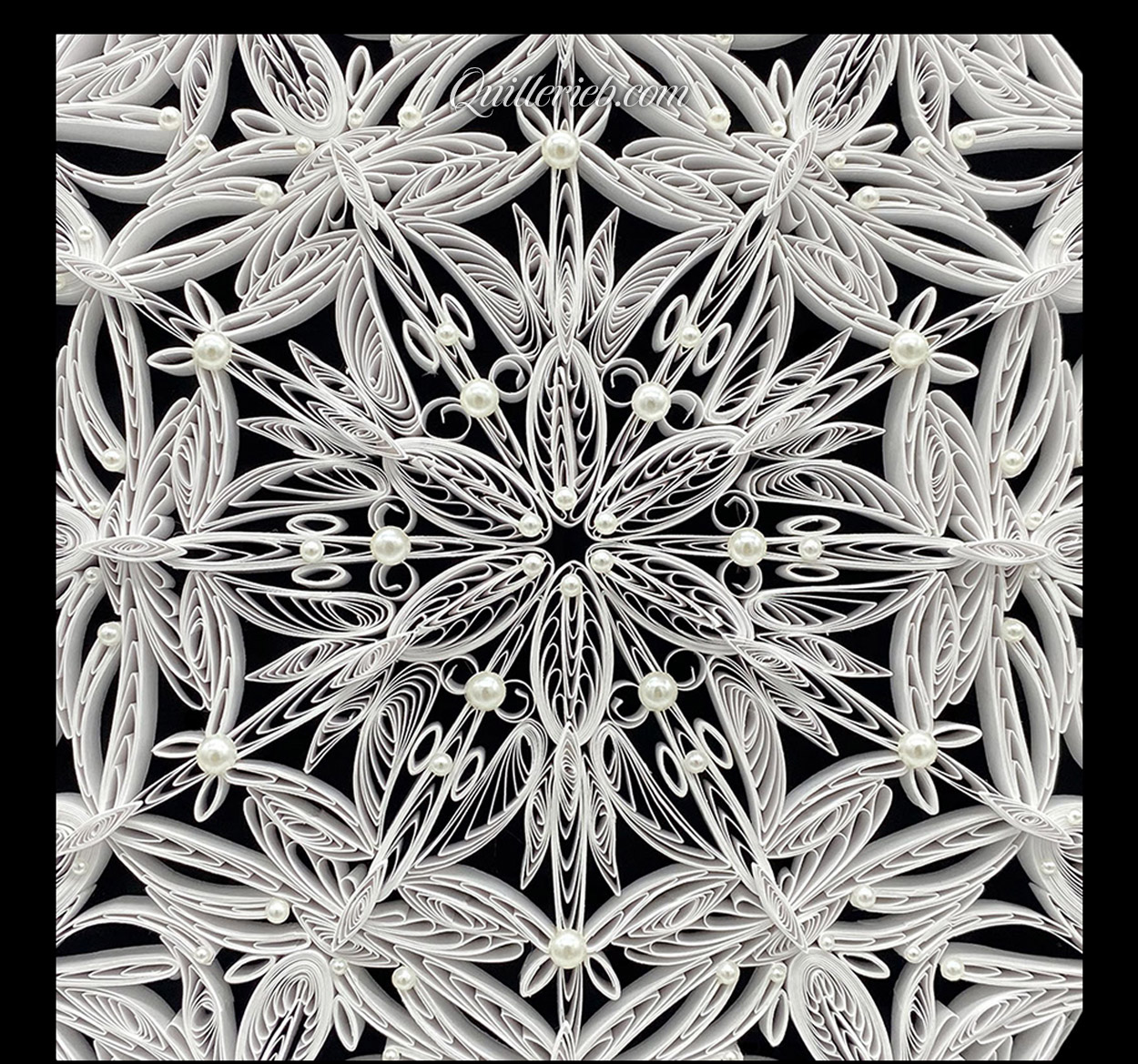 Circular 6-pointed quilling in white, snowflake design close-up view.