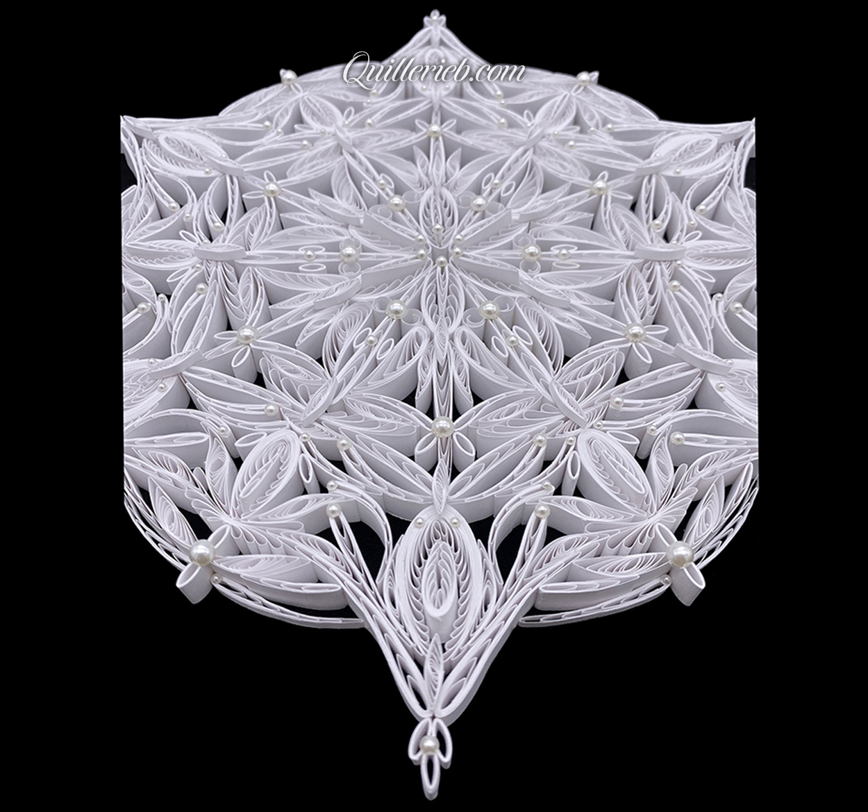 Circular 6-pointed quilling in white, snowflake design slanted backwards view.