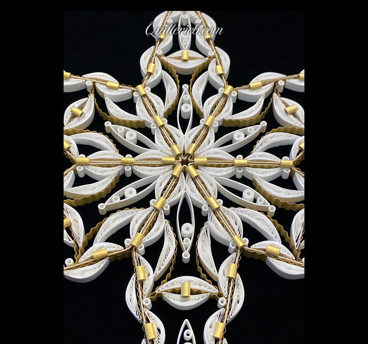 Rounded six-Point Star quilling design in white with elements of gold tones close-up center angled backwards view.