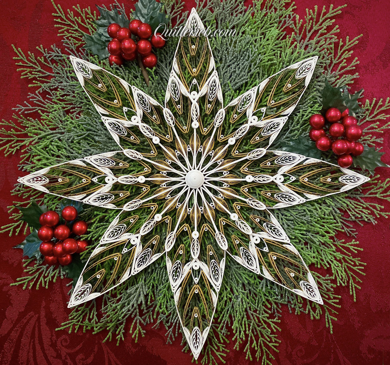 8-Point Star quilling design in brown and white tones on green floral mat with red berries full view.